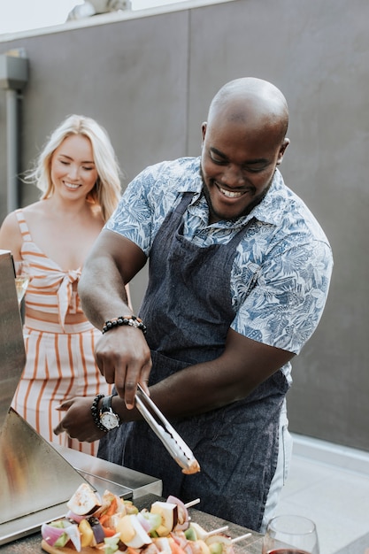 Gelukkig paar die barbecuevleespennen voorbereiden