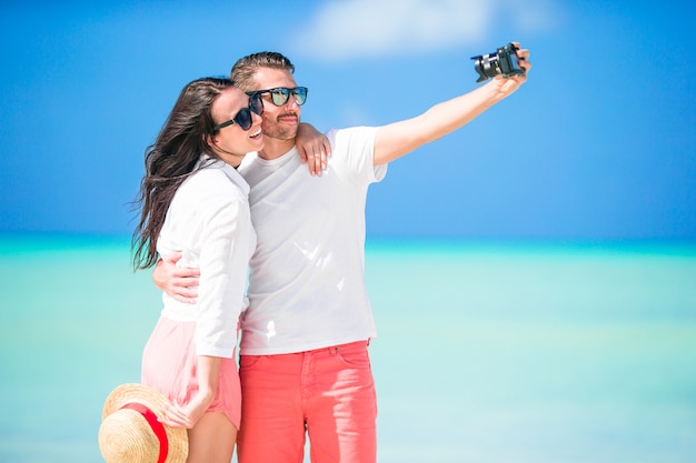 Gelukkig paar die een selfiefoto op wit strand nemen