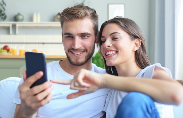 Gelukkig paar die media van inhoud in een slimme telefoonzitting thuis genieten op een laag