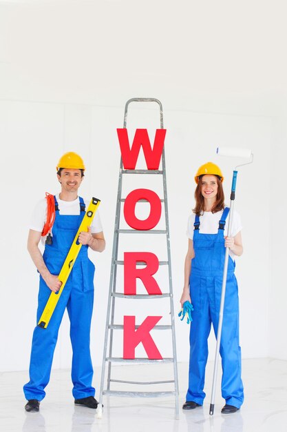 Gelukkig paar in uniforme holdingshulpmiddelen en ladder met werkbrieven