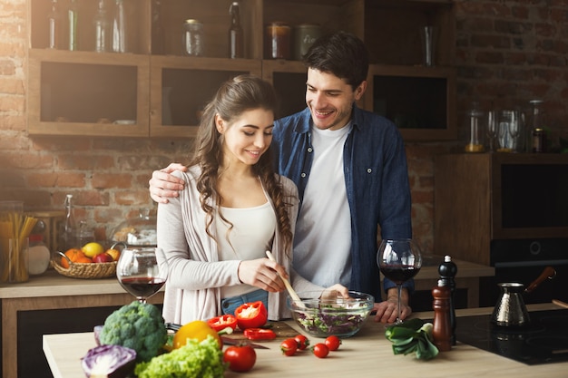 Gelukkig paar koken samen diner in hun loft keuken thuis. Groentesalade bereiden.