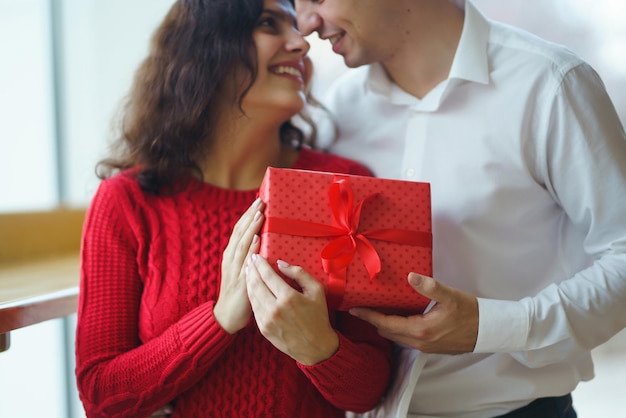 Gelukkig paar met cadeau knuffelen Rode geschenkdoos in de handen van een verliefd paar Valentijnsdag