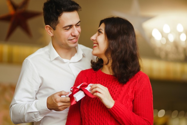 Gelukkig paar met cadeau knuffelen Rode geschenkdoos in de handen van een verliefd paar Valentijnsdag