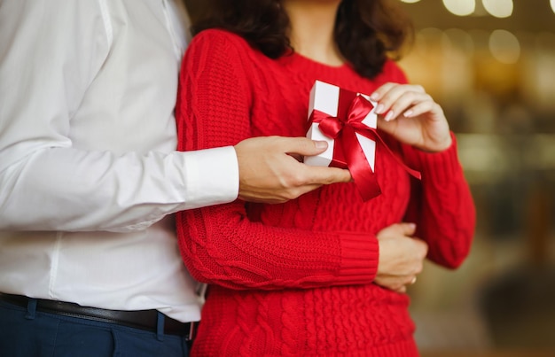 Gelukkig paar met cadeau knuffelen Rode geschenkdoos in de handen van een verliefd paar Valentijnsdag