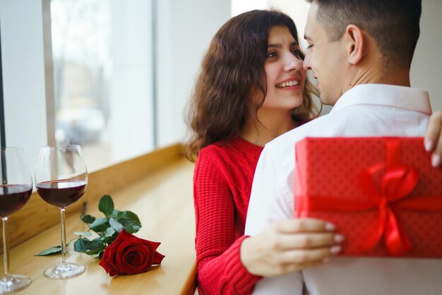 Gelukkig paar met cadeau knuffelen Rode geschenkdoos in de handen van een verliefd paar Valentijnsdag