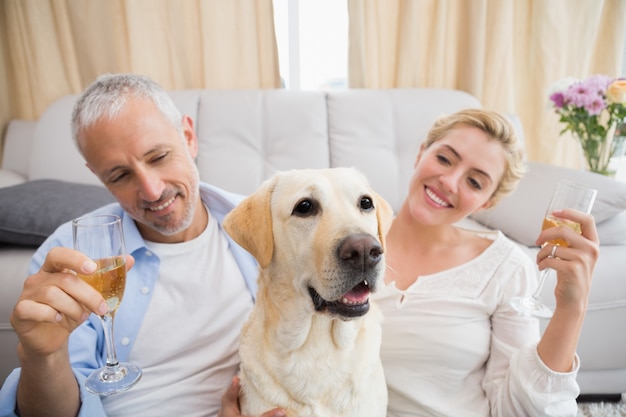 Gelukkig paar met hun huisdierenhond het drinken champagne