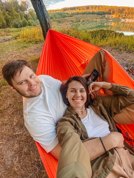 gelukkig paar rusten in de hangmat buiten het nemen van selfie