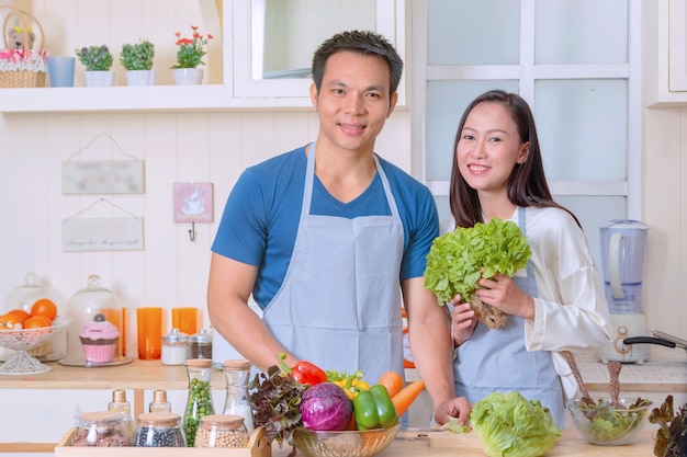 Gelukkig paar samen koken, Man en vrouw in de keuken die plantaardige salade voorbereiden