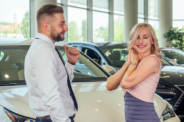 Gelukkig paar staat voor nieuwe auto man bedekte vrouw ogen in showroom verrast cadeau auto