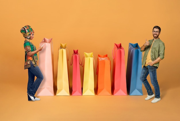 Gelukkig paar van gemengd ras dat online winkelt bij enorme tassen