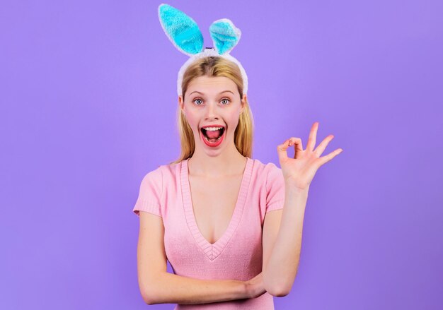 Gelukkig paasmeisje dat teken toont oke glimlachende vrouw in konijnenoren met ok gebaar lentevakantie