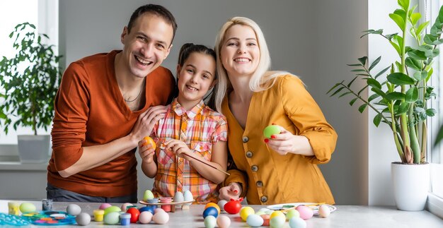 Gelukkig Pasen! familie moeder, vader en kinderen die plezier hebben, schilderen en versieren eieren voor vakantie.