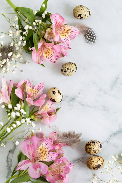 Foto gelukkig pasen kwarteleitjes veren lente roze bloemen op marmeren achtergrond vertical