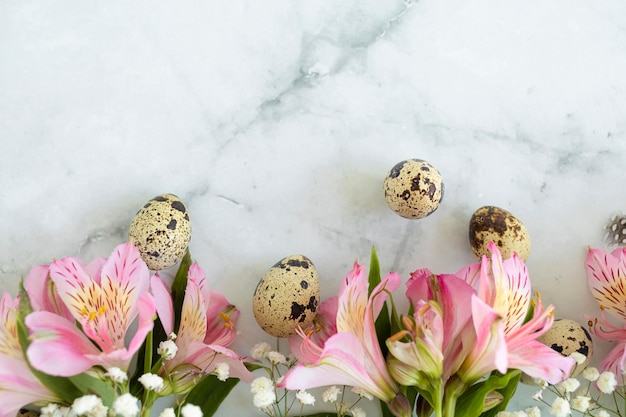 Foto gelukkig pasen kwarteleitjes veren lente roze bloemen op marmeren achtergrond