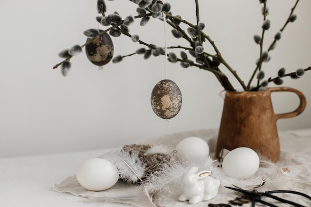 Gelukkig Pasen Natuurlijke eieren konijn beeldjes veren nest wilgentakken in vaas op tafel