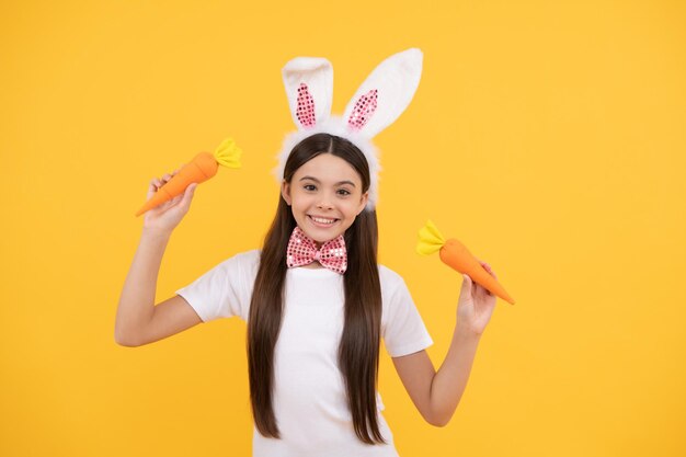 Gelukkig Pasen tienermeisje in konijnenoren en vlinderdas houden wortel, Pasen.