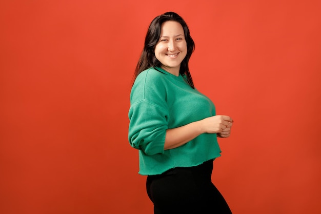 Gelukkig plus size positieve vrouw. gelukkig lichaam positief concept. ik hou van mijn lichaam. aantrekkelijke overgewicht vrouw die zich voordeed op camera in de studio op een gekleurde achtergrond. meisje draagt een trui