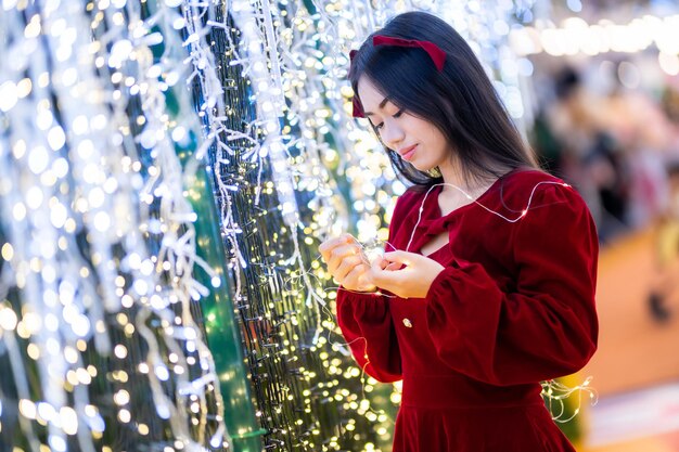 Gelukkig portret jonge Aziatische vrouw Santa kostuum en kerst groeten foto perceel decoratie op kerstboom licht Abstracte circulaire bokeh achtergrond Decoratie tijdens Kerstmis en Nieuwjaar.