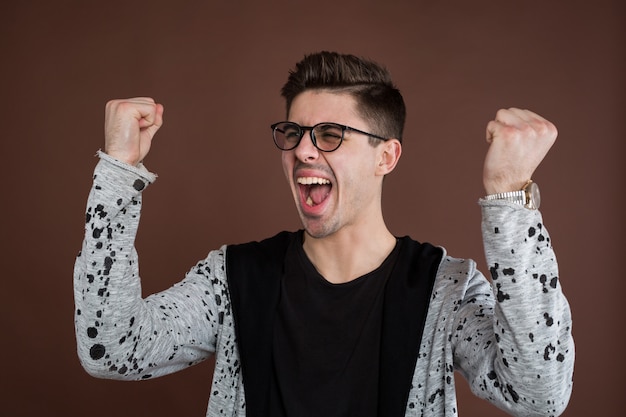 Gelukkig positief opgewonden jongeman balde vuisten en schreeuwen