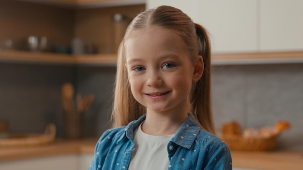 Gelukkig positief portret thuis vrolijk zorgeloos blank schattig s klein meisje in de keuken glimlachend