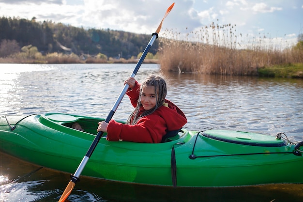 Gelukkig preteen meisje kajakken op rivier peddel in de hand zomerkamp activiteit extreme sport