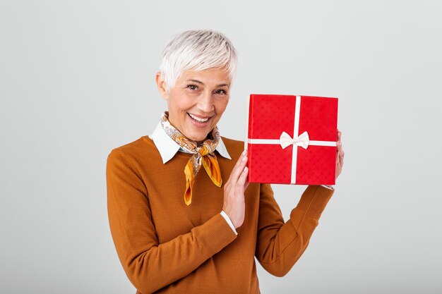 Gelukkig rijpe vrouw met geschenkdoos en ernaar kijken