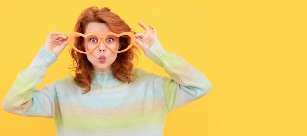 Gelukkig roodharig meisje draagt een grappige feestbril op een gele achtergrondfeest vrouw geïsoleerd gezicht portret banner met kopie ruimte