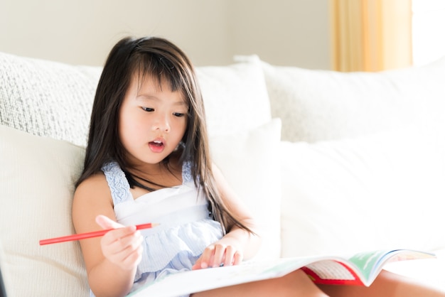 Gelukkig schattig klein meisje glimlachend en rood potlood schrijven op een boek te houden