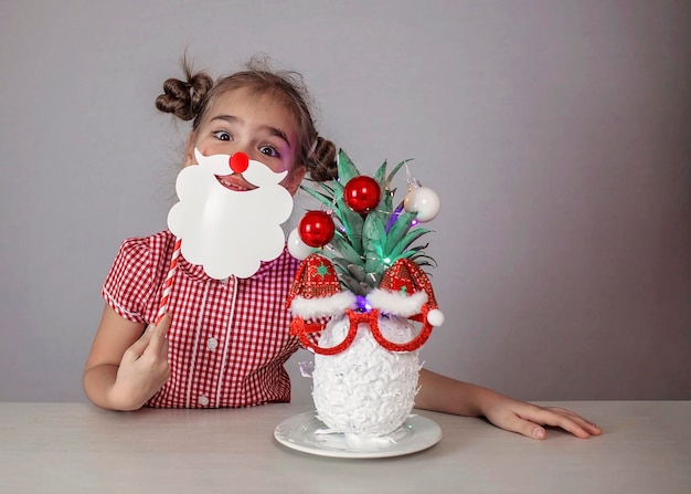 Gelukkig schattig klein meisje in de buurt van het gezicht van de kerstman gemaakt met ananas