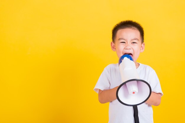 Gelukkig schattig klein vrolijk kind dat vasthoudt en schreeuwt of schreeuwt door de megafoon