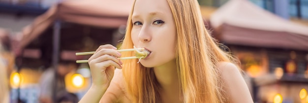 Gelukkig schattig meisje dat straatvoedsel eet en er leuk uitziet in een traditionele kleine eerlijke banner lang