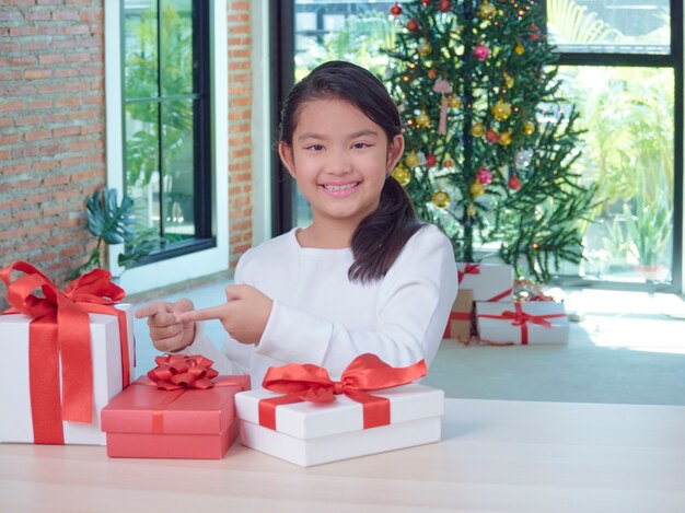 Gelukkig schattig meisje met geschenkdozen thuis met feestelijke decoraties.