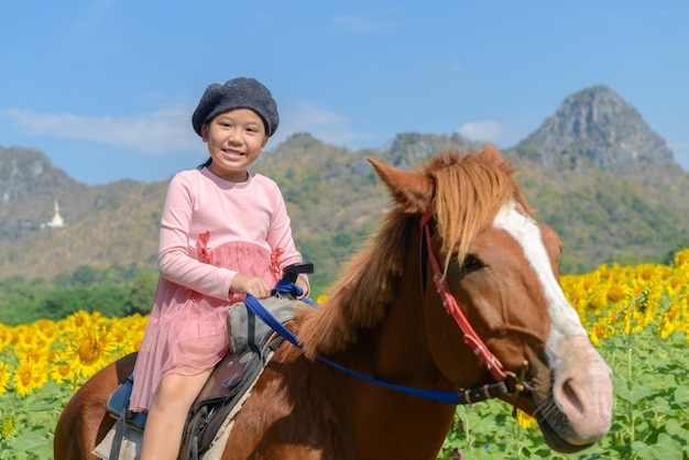 Gelukkig schattig meisje paard rijden in zonnebloem veld