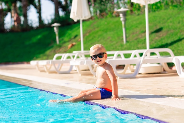 Gelukkig schattige babyjongen plezier bij het zwembad in het vakantieoord