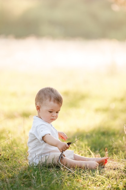 Gelukkig schattige babyjongen zittend op het gras in het park