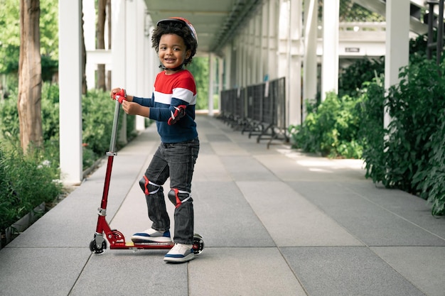 Gelukkig schattige jongen met afro-haar speel scooter