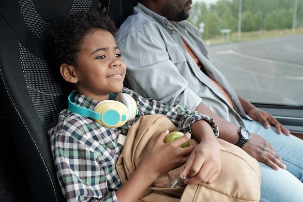 Gelukkig schattige kleine jongen met appel en rugzak zitten in de bus
