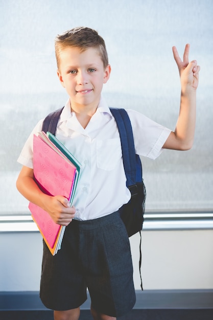 Gelukkig schoolkind boeken houden en staan in de klas