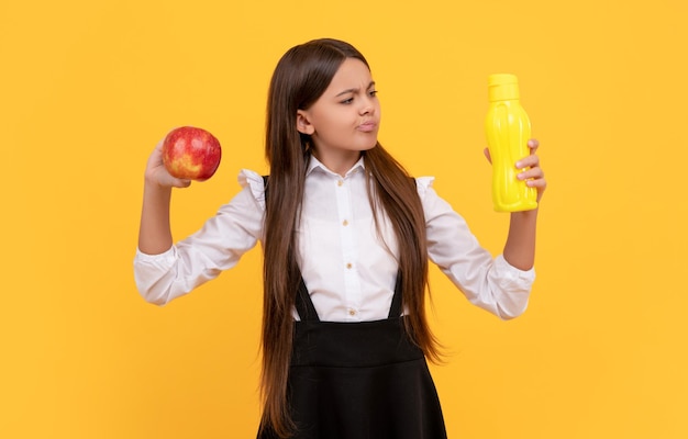 Gelukkig schoolkind in uniform houdt appel en waterfles lunchpauze vast