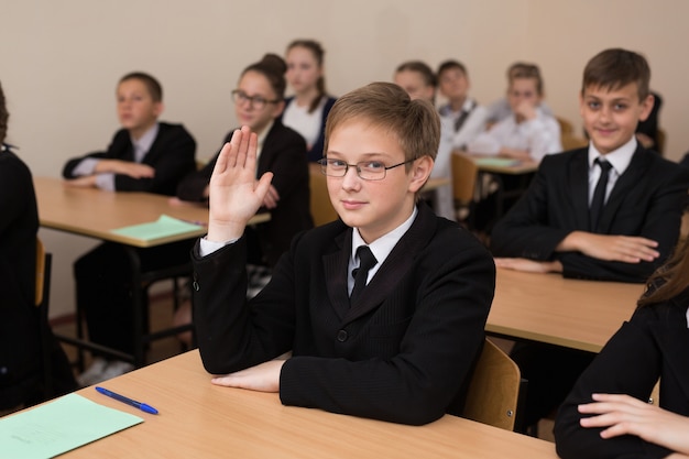 Gelukkig schoolkinderen zitten aan een bureau in de klas