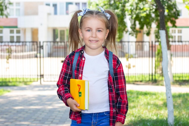 Gelukkig schoolmeisje met een leerboek in haar handen. in een wit T-shirt en een geruit overhemd