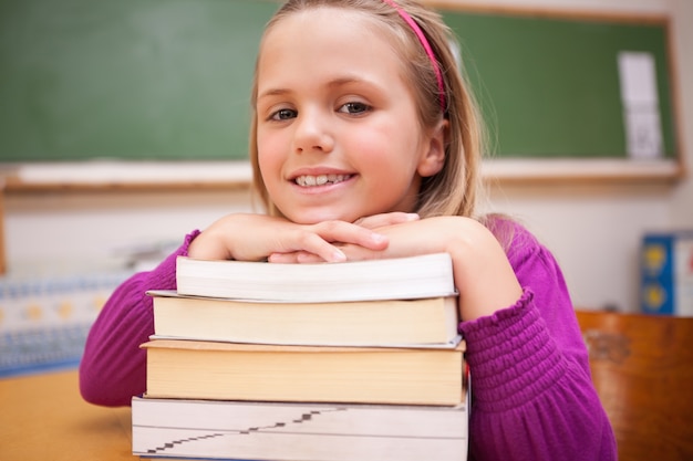 Gelukkig schoolmeisje poseren met een stapel boeken