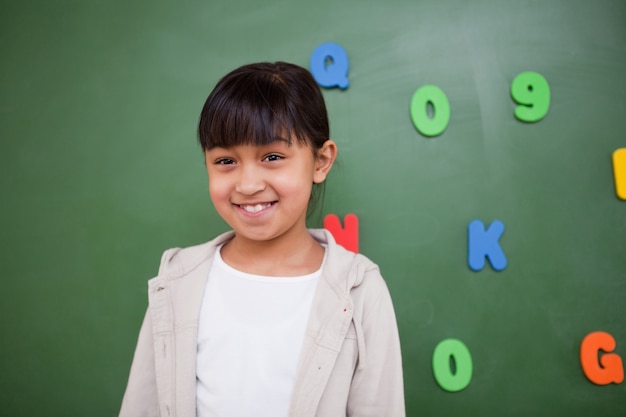 Gelukkig schoolmeisje poseren voor een schoolbord