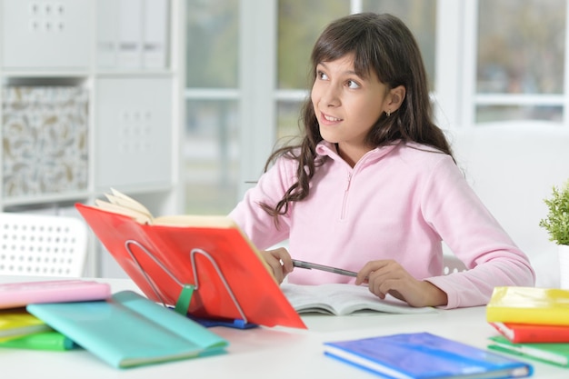 Gelukkig schoolmeisje zittend aan een bureau en studeren