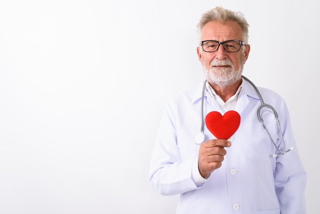 gelukkig senior bebaarde man arts glimlachen terwijl rood hart op wit