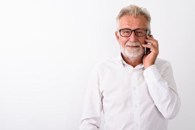 gelukkig senior bebaarde man die lacht tijdens het gesprek op de mobiele telefoon met een bril op wit