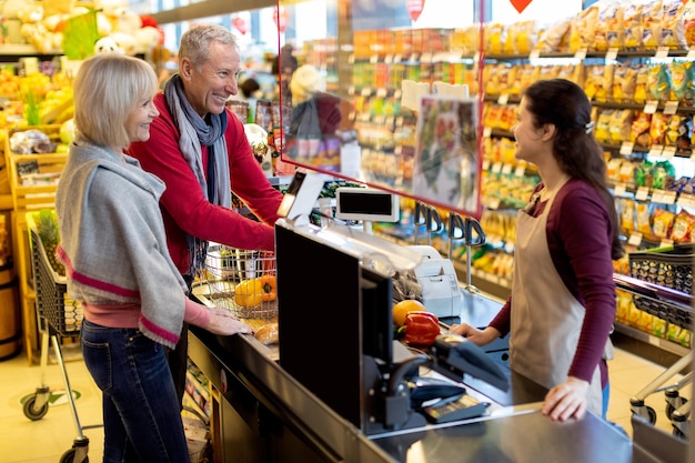 Gelukkig senior man en vrouw in gesprek met kassier