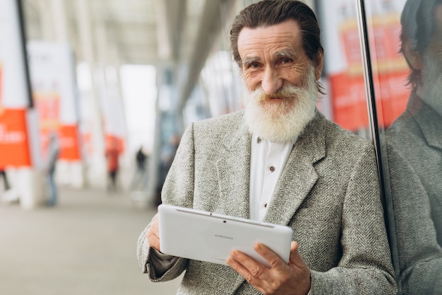 Gelukkig senior man met de tablet op de kantoorgebouwen