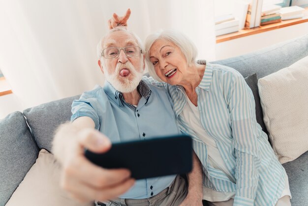 Gelukkig senior paar dat plezier heeft en foto's maakt op mobiele telefoon om online te delen