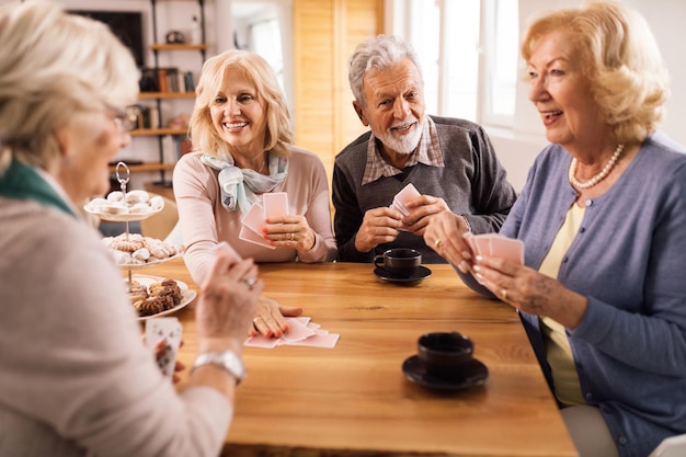 Gelukkig senior paar dat plezier heeft tijdens het kaarten met vrienden thuis